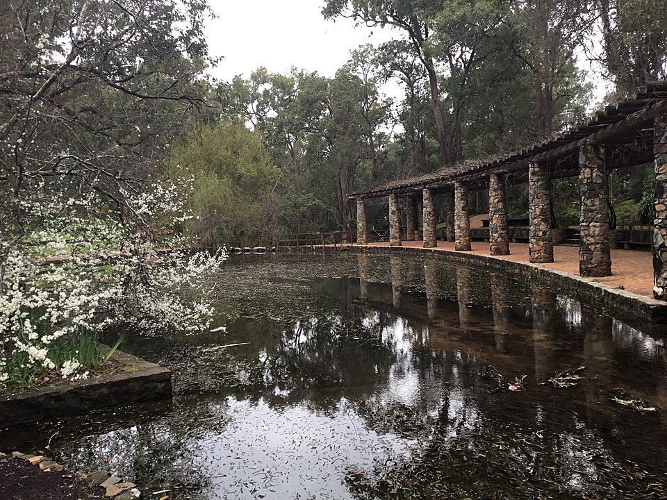 Stone colonnade reflected in a pond at Araluen
