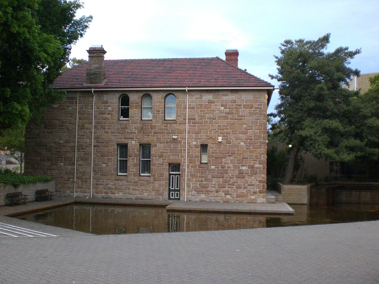 Stone former Police Courts building used by AGWA’s Centenary Galleries, with a tiled roof and reflecting pool in an archive photograph.