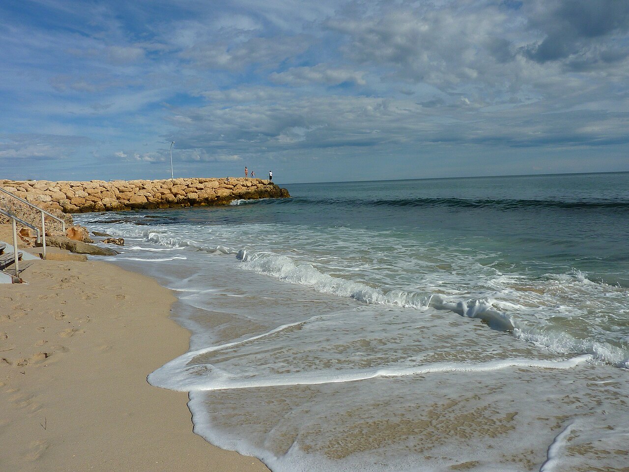 Waves washing onto Sorrento Beach beside a rock groyne.