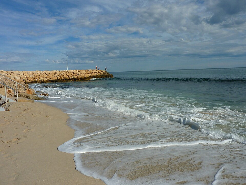 Waves washing onto Sorrento Beach beside a rock groyne.