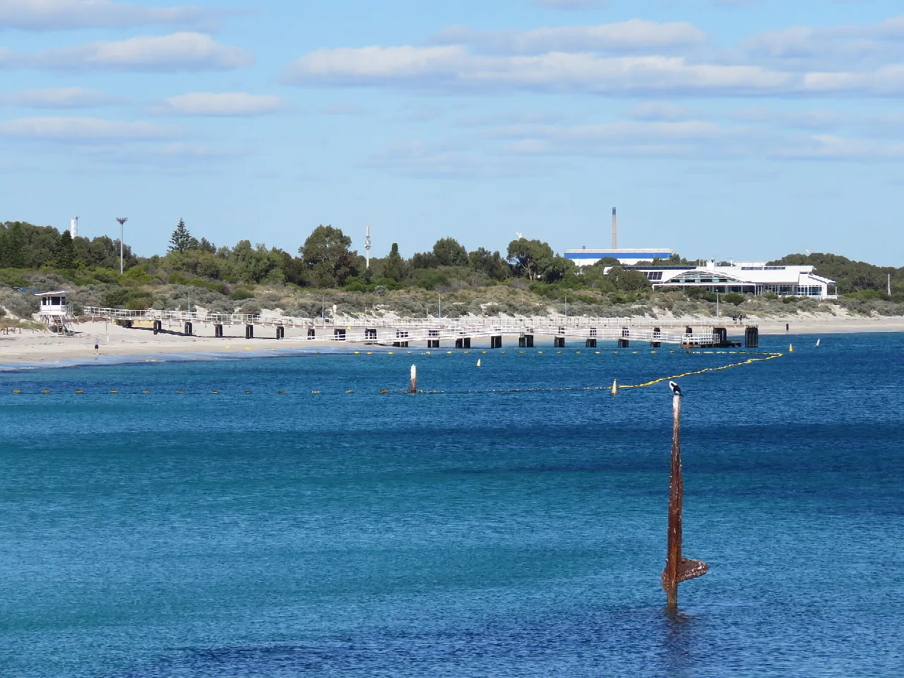 Rusting remains of the Omeo shipwreck near shore at North Coogee, with Coogee Beach Jetty behind.