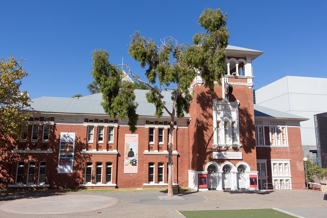 PICA's red-brick facade and tower, with white window surrounds and trees in front.