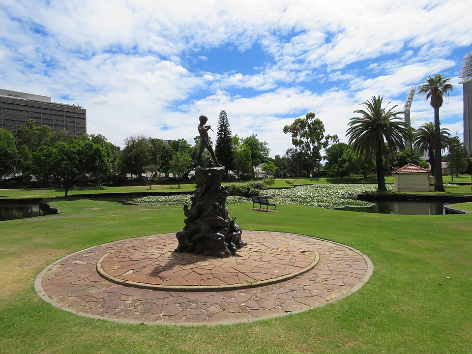 Peter Pan statue with trees and lawns in Queens Gardens