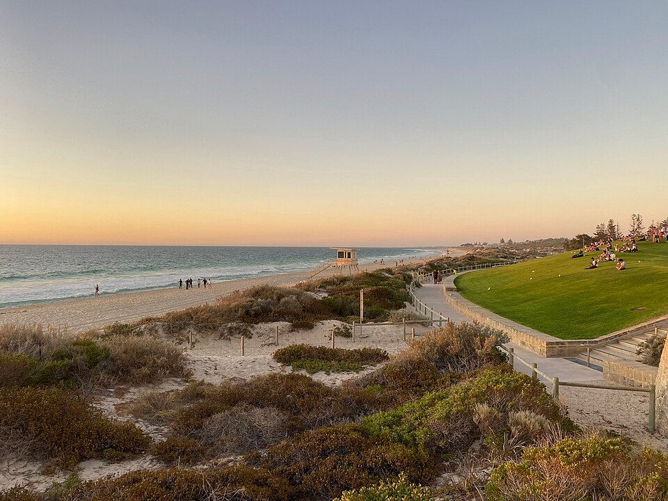 Scarborough beachfront at sunset, with a path and lawn by the sea.