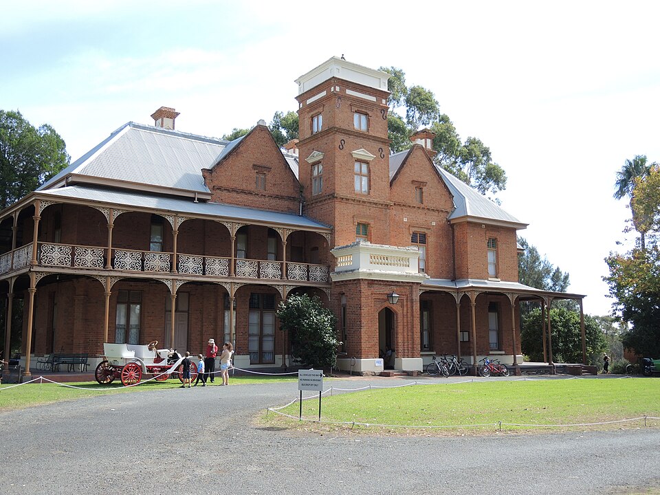 Two-storey Woodbridge House with verandahs and a central tower.